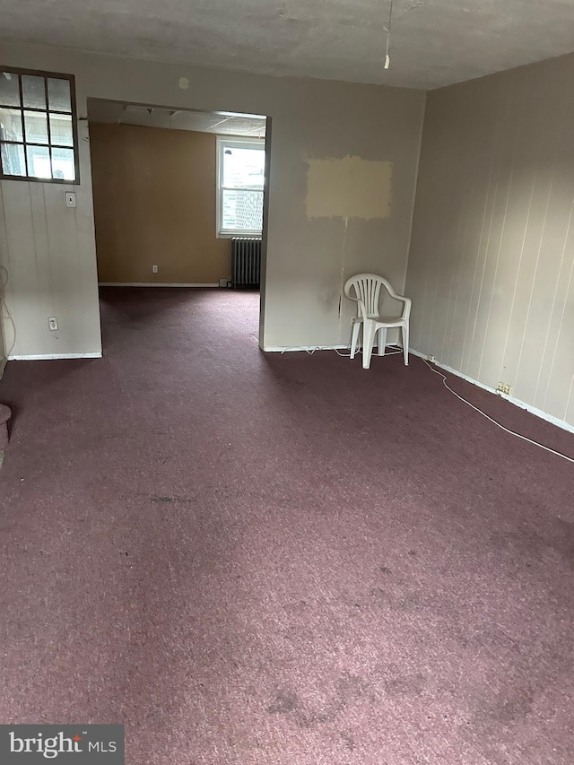 carpeted empty room featuring radiator heating unit