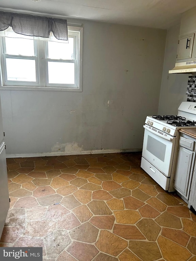 kitchen with under cabinet range hood, stone finish floor, and white range with gas cooktop