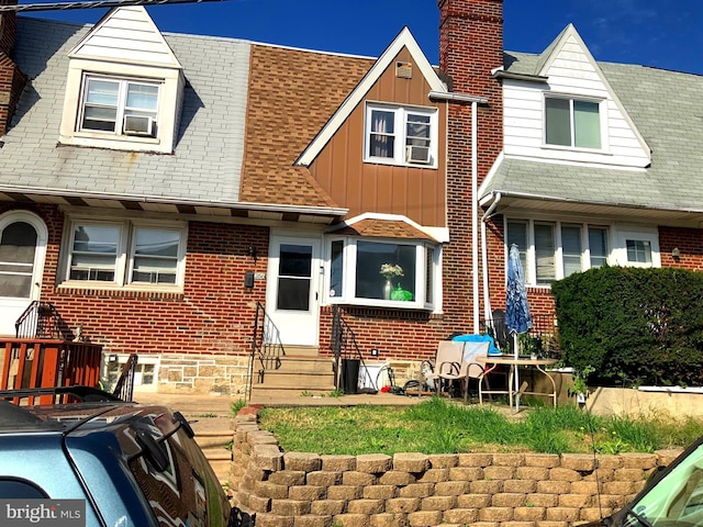rear view of property with a chimney, entry steps, board and batten siding, and brick siding