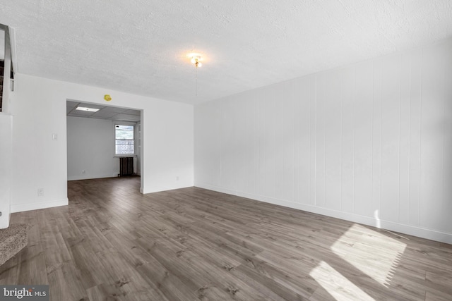 unfurnished room featuring radiator, wood finished floors, and a textured ceiling