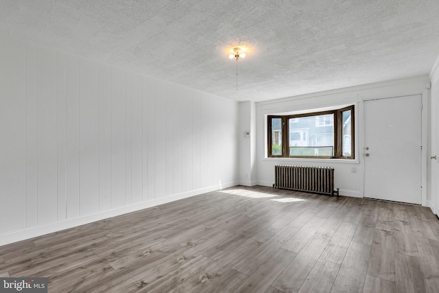interior space with baseboards, radiator, wood finished floors, and a textured ceiling