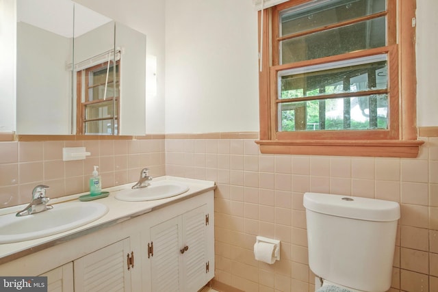 bathroom with toilet, a sink, and tile walls
