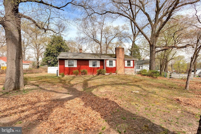 ranch-style house featuring a chimney and fence