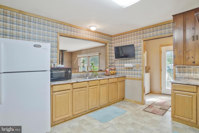 kitchen featuring freestanding refrigerator, black microwave, ornamental molding, a sink, and wallpapered walls