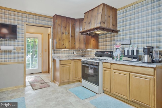 kitchen featuring baseboards, premium range hood, white gas stove, wallpapered walls, and decorative backsplash