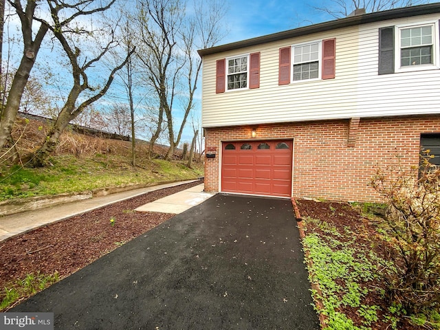 view of property exterior with brick siding, an attached garage, and driveway