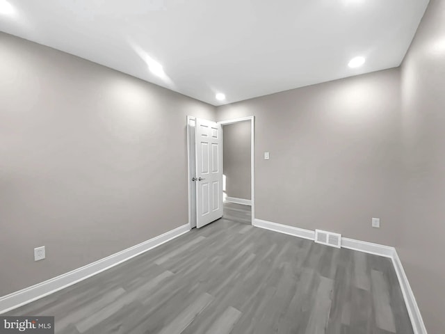 unfurnished room with wood finished floors, baseboards, and visible vents