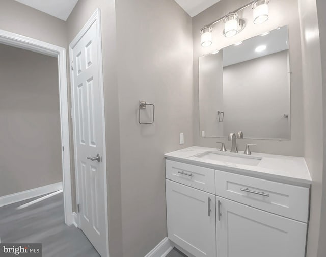bathroom with baseboards, vanity, and wood finished floors