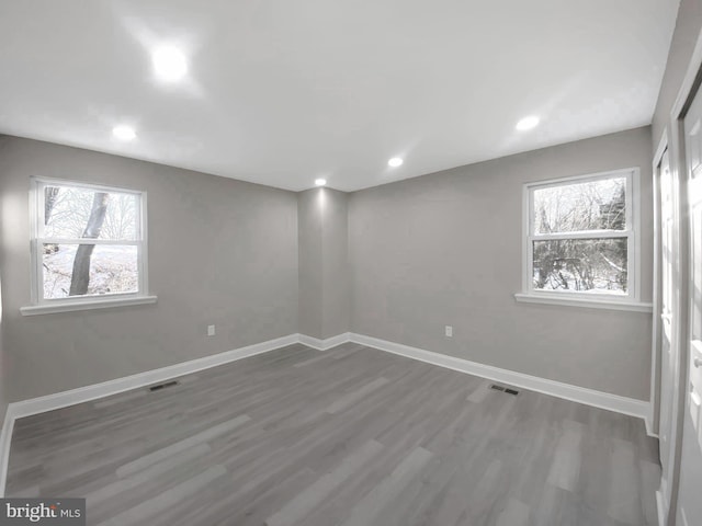 basement with a wealth of natural light, visible vents, baseboards, and wood finished floors
