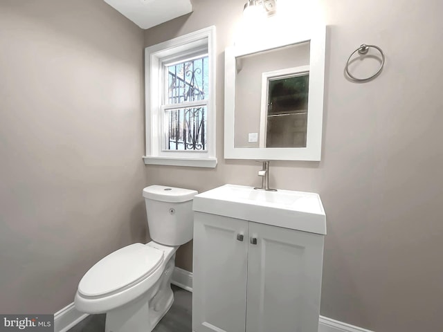 bathroom featuring toilet, vanity, and baseboards