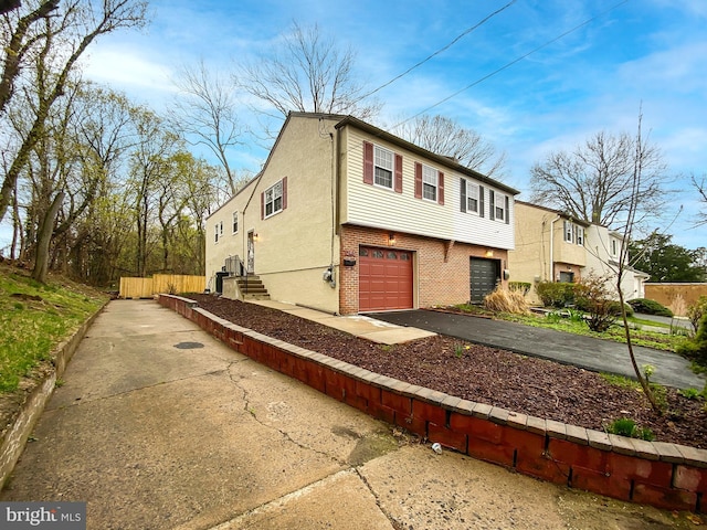 exterior space with a garage, brick siding, driveway, and stucco siding