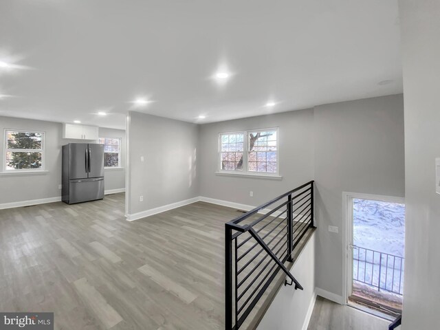 basement with light wood finished floors, freestanding refrigerator, baseboards, and recessed lighting