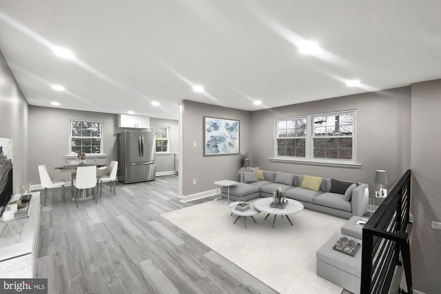 living room with baseboards, light wood-type flooring, recessed lighting, and a healthy amount of sunlight
