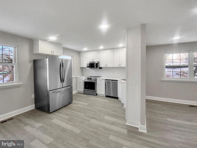 kitchen featuring light countertops, white cabinets, light wood-style floors, visible vents, and stainless steel appliances