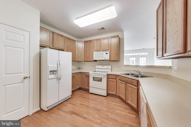 kitchen featuring visible vents, white appliances, light wood-style floors, light countertops, and a sink