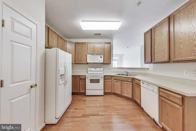 kitchen with visible vents, a sink, light countertops, light wood finished floors, and white appliances