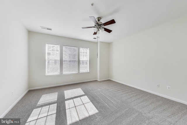 carpeted empty room featuring visible vents, baseboards, and ceiling fan