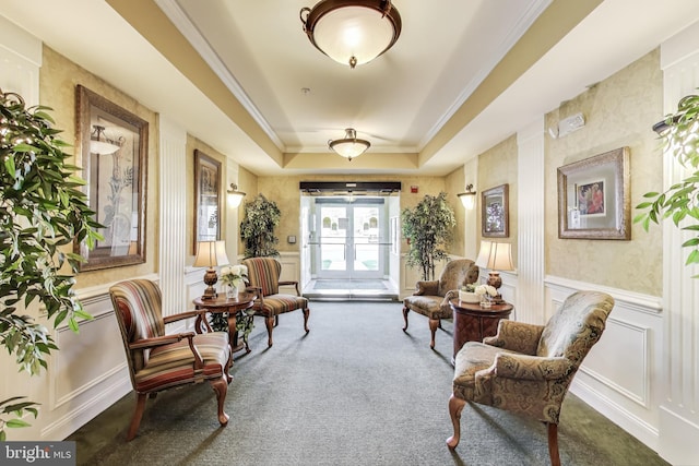living area featuring carpet floors, a tray ceiling, ornamental molding, and a decorative wall