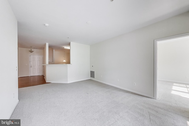 unfurnished living room with carpet floors, baseboards, and visible vents