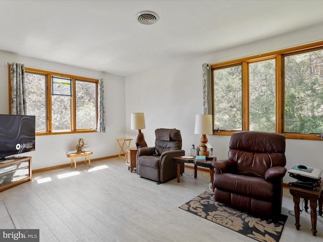 living area with light wood-style floors, visible vents, and baseboards