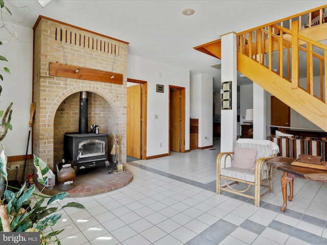 living room with tile patterned floors, a wood stove, baseboards, and stairs