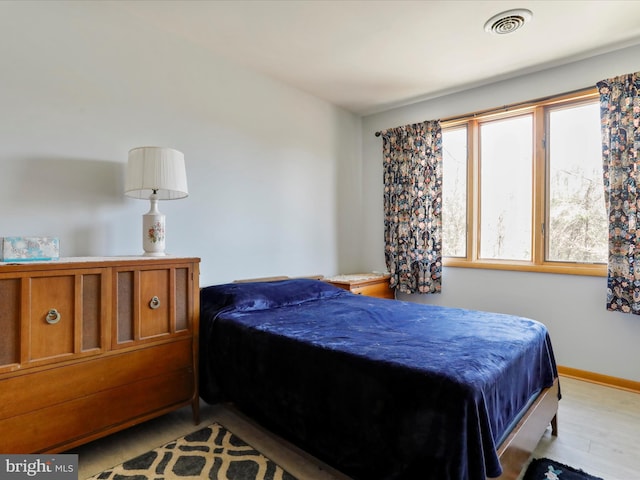 bedroom with wood finished floors, baseboards, and visible vents