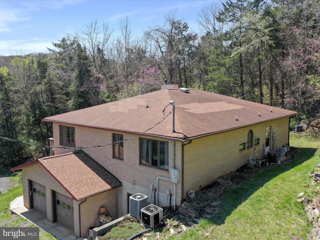 view of side of home with brick siding, a shingled roof, a lawn, and central air condition unit
