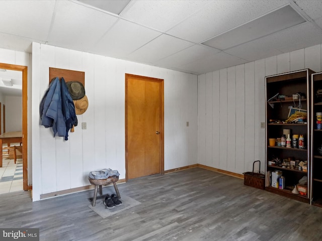 interior space featuring a paneled ceiling, baseboards, and wood finished floors