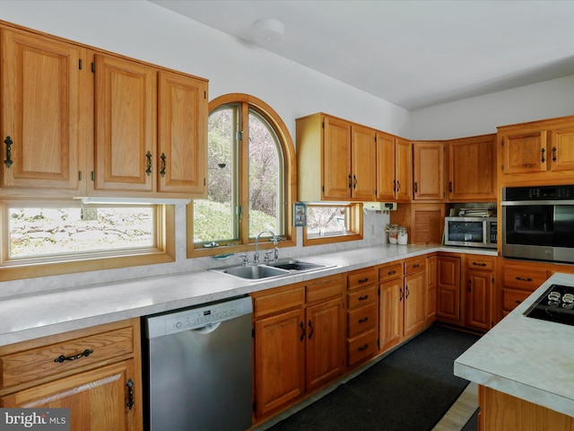 kitchen with a sink, brown cabinetry, light countertops, and stainless steel appliances