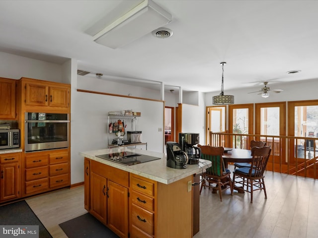 kitchen featuring visible vents, a center island, light countertops, light wood finished floors, and stainless steel appliances