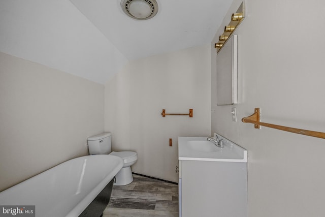 bathroom with wood finished floors, vanity, a freestanding tub, toilet, and lofted ceiling