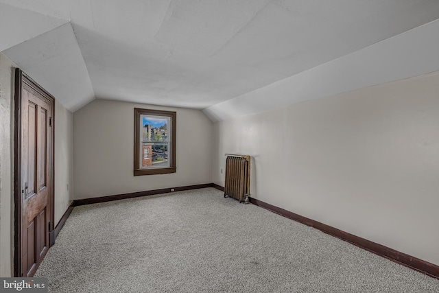 additional living space with radiator heating unit, light carpet, baseboards, and lofted ceiling