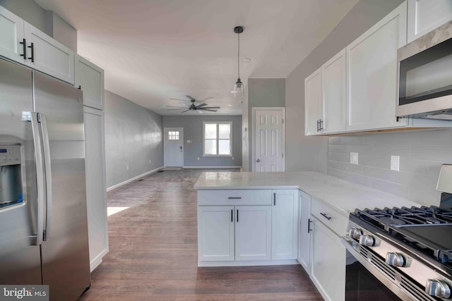 kitchen featuring white cabinets, appliances with stainless steel finishes, a ceiling fan, a peninsula, and backsplash