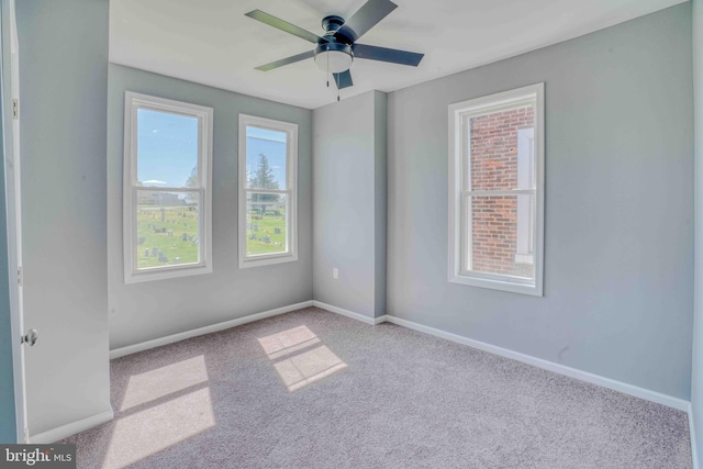 carpeted spare room with baseboards and a ceiling fan