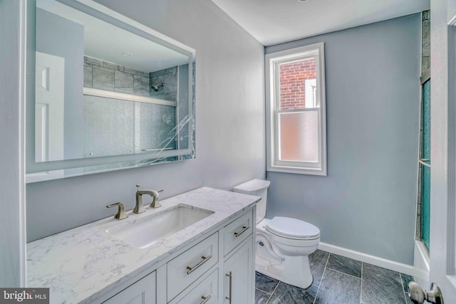 full bathroom featuring toilet, vanity, a shower with shower door, and baseboards