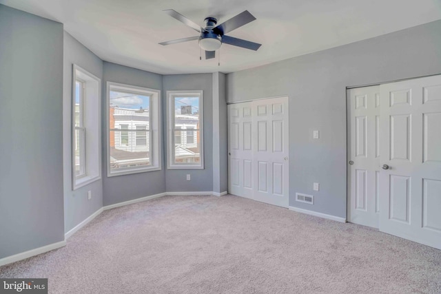 unfurnished bedroom with carpet flooring, visible vents, baseboards, and multiple closets