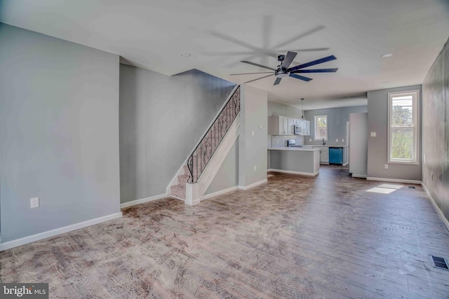 unfurnished living room with baseboards, stairway, a ceiling fan, visible vents, and wood finished floors