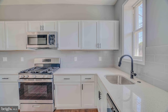 kitchen with a sink, white cabinetry, plenty of natural light, and stainless steel appliances