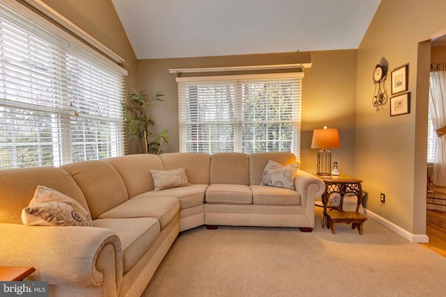 living area with light carpet, baseboards, and lofted ceiling