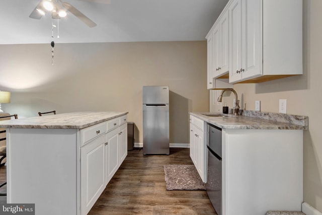 kitchen featuring dark wood-style floors, freestanding refrigerator, a ceiling fan, white cabinets, and a sink
