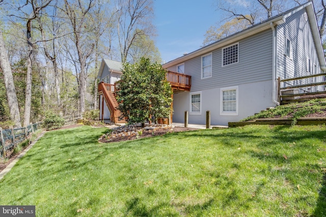 rear view of property with stairway, a deck, fence, and a lawn
