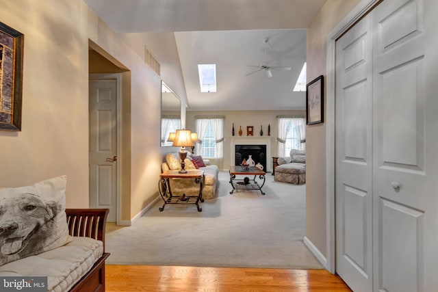 living room with vaulted ceiling with skylight, ceiling fan, baseboards, and visible vents