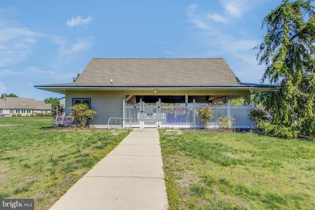 farmhouse with a shingled roof, a fenced front yard, and a front lawn