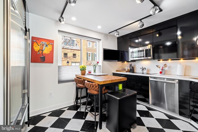 331 S 2nd St, Philadelphia, PA 19106 - kitchen with stainless steel appliances, tile patterned floors, a sink, and dark cabinetry