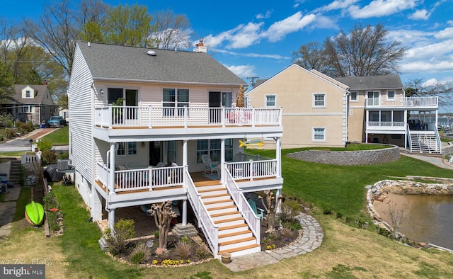 rear view of property featuring stairway, a chimney, and a lawn