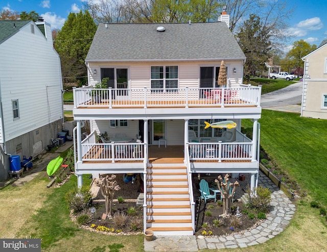rear view of property with stairs, a shingled roof, a chimney, and a lawn