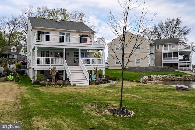 rear view of house with a balcony, stairs, and a lawn