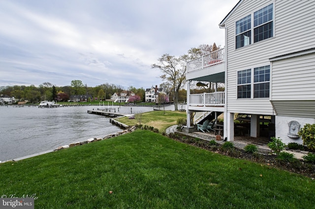 dock area with a water view, stairway, and a yard