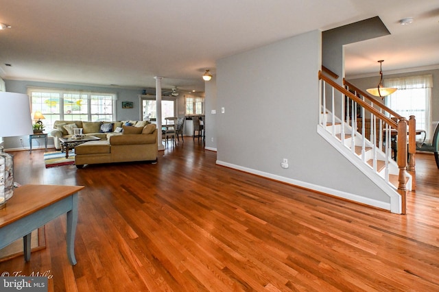 living room featuring baseboards, ceiling fan, crown molding, stairway, and wood finished floors