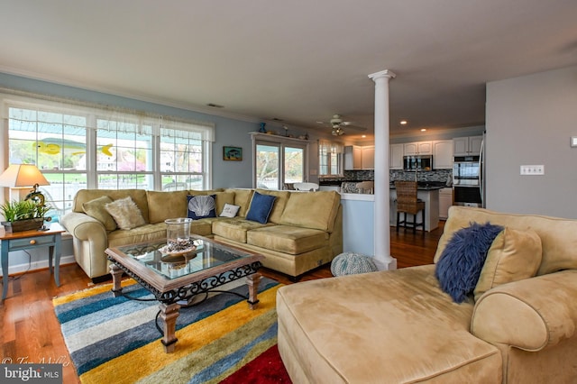 living room featuring crown molding, ornate columns, a ceiling fan, visible vents, and wood finished floors